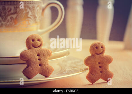 Happy gingerbread uomini seduti con antichi teacups e piattini Foto Stock