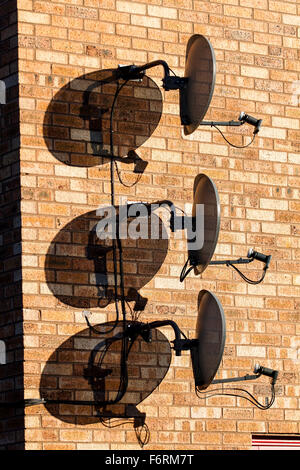 Tre Sky TV satellite digitale piatti insieme fissato verticalmente al di sopra di ogni altro su di un moderno muro di casa a Dundee, Regno Unito Foto Stock