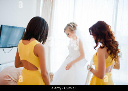 Dolce sposa bionda con damigelle in abito giallo Foto Stock