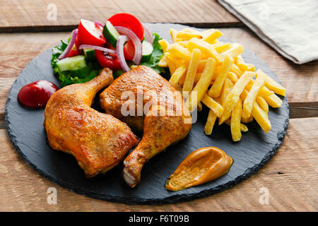 Arrosto di cosce di pollo con patatine fritte e insalata mista Foto Stock