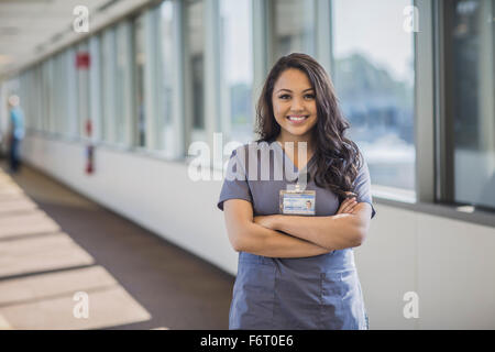 Razza mista infermiera sorridente in ospedale in corridoio Foto Stock