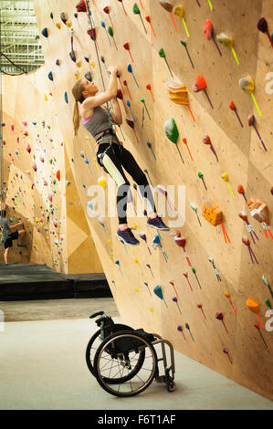 Donna paraplegici arrampicata in palestra Foto Stock