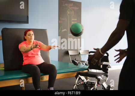 Donna disabile facendo terapia fisica con trainer Foto Stock