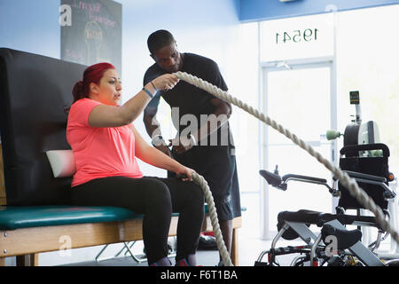 Donna disabile facendo terapia fisica con trainer Foto Stock
