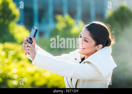 Donna ispanica tenendo selfie con un telefono cellulare Foto Stock