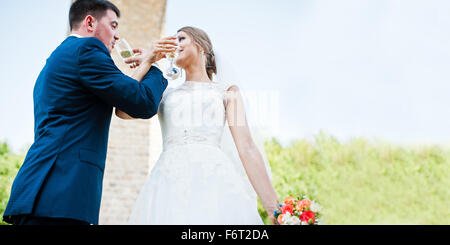 Moda e matrimonio felice di bere champagne da bicchieri sotto il ponte di pietra Foto Stock