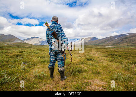 Mari hunter crossbow portante nel campo remoto Foto Stock