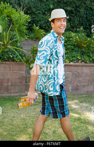 Uomo che porta lattine di birra in cortile Foto Stock