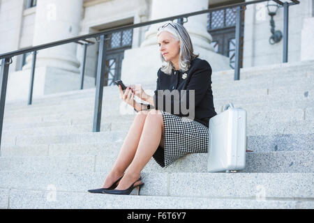 Imprenditrice caucasica tramite telefono cellulare sulle Courthouse passi Foto Stock