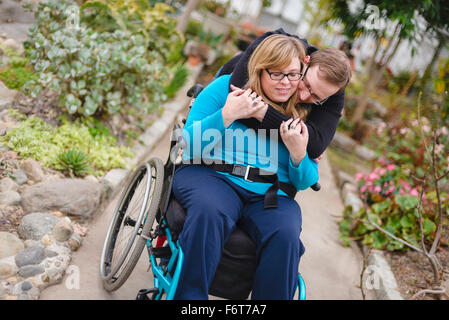 Abbracci uomo paraplegico ragazza in giardino Foto Stock