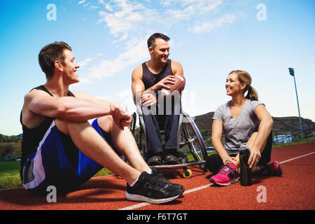 Atleta paraplegico in sedia a rotelle e amici su via Foto Stock