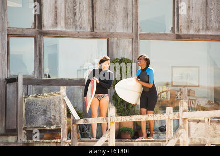Le donne che trasportano le tavole da surf sul ponte Foto Stock