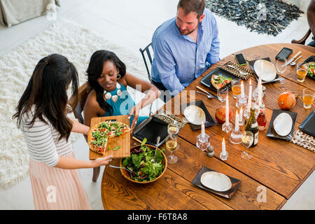 Donna che serve agli amici a cena Foto Stock