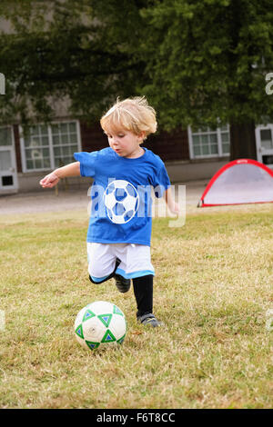 Ragazzo caucasico che giocano a calcio nel campo Foto Stock