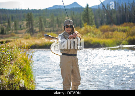 La donna caucasica la pesca nel fiume rurale Foto Stock