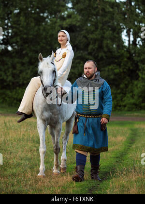 Coppia sposata vestito in abiti dei vichinghi giocando con un cavallo Foto Stock