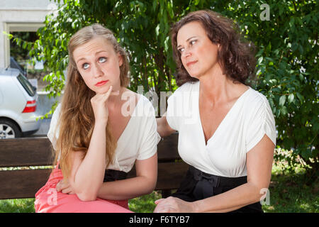 Due donne aventi argomento su una panchina nel parco Foto Stock