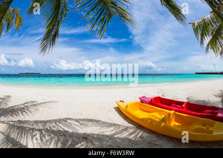 Il rosso e il giallo kayak sulla spiaggia sotto le palme di cocco Foto Stock