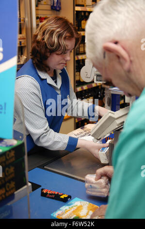 Shop assistant con disabilità nell'apprendimento di servire il cliente al supermercato checkout, Foto Stock