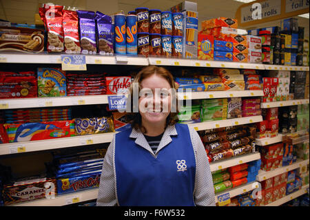 Ritratto di shop assistant con disabilità di apprendimento in piedi di fronte a scaffali di biscotti nel supermercato sorridente, Foto Stock