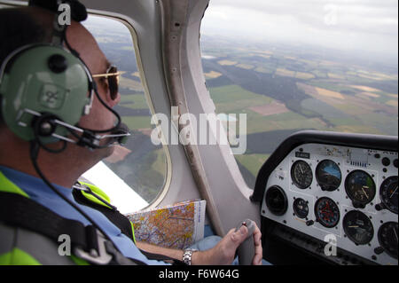 Uomo con disabilità; chi è utente su sedia a rotelle; seduto in cabina di pilotaggio di aeromobili; indossa gli auricolari e il boccaglio; piano di volo, Foto Stock