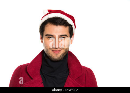 Giovane bella bruna uomo che indossa red capanna, cappotto nero e pullover, sorridendo felice, su sfondo bianco con spazio di copia Foto Stock