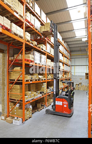 Un carrello elevatore a forche compatto e ad alto sbraccio rimuove le merci su un pallet da scaffalature di alto livello in un moderno magazzino di stoccaggio Foto Stock