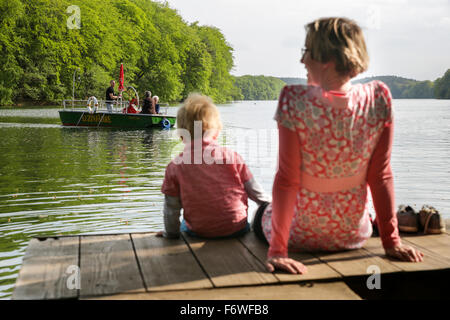 La madre e il Figlio seduto su di un molo al lago Schmaler Luzin, fune ferry in background, Feldberger Seenlandschaft, Mecklenburg-Weste Foto Stock