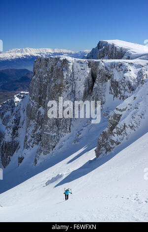 Backcountry femmina sciatore salendo attraverso coperta di neve cirque a Monte Sirente, Maiella gamma in background, Valle Lupara, Abru Foto Stock