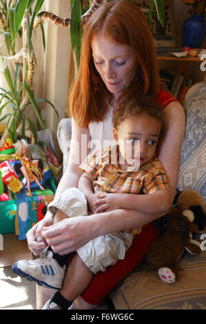 Madre mettendo la sua scarpe da bambino su, Foto Stock