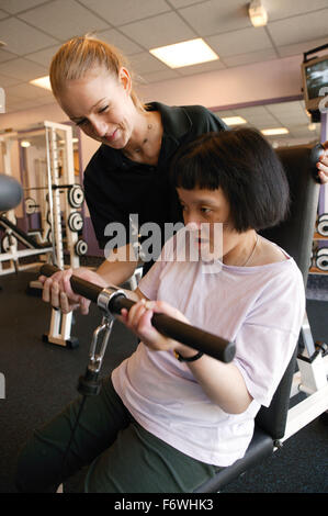 Accesso ai servizi, istruttori di fitness e ragazza di disabili in palestra; utilizzando il cavo giungla, Foto Stock