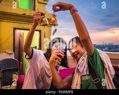 Bangkok, Tailandia. Xx Nov, 2015. Ragazze prendete ''selfies'' con un iPhone della preghiera campane hanno donato al chedi sulla parte superiore del Wat Saket durante l'annuale Fiera del tempio. Wat Saket è su un uomo fatto collina nella parte storica di Bangkok. Il tempio è golden guglia che è 260 metri di altezza che è stato il punto più alto di Bangkok per più di cento anni. Il tempio la costruzione iniziò nel 1800 durante il regno del Re Rama III e fu completata durante il regno del Re Rama IV. Credito: ZUMA Press, Inc./Alamy Live News Foto Stock