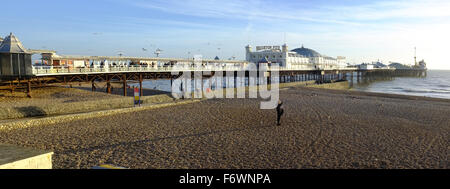 Un panorama del molo di Brighton con un uomo in piedi sulla spiaggia di fronte. Foto Stock