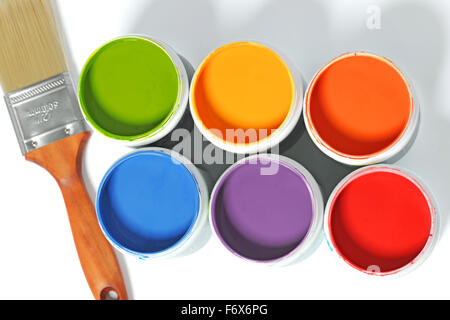 Le lattine di diversi colori e pennello su sfondo chiaro Foto Stock