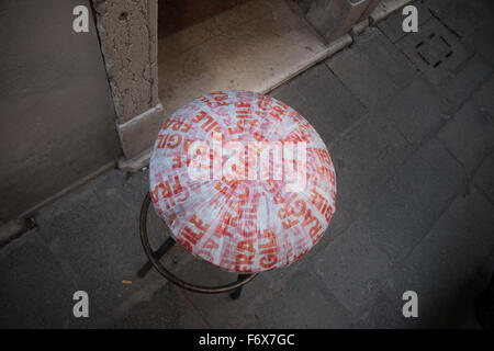 Sgabello rotondo con seduta in stoffa a lettere rosse su pavimentazione in pietra visto dall'alto a Venezia, Veneto, Italia Foto Stock