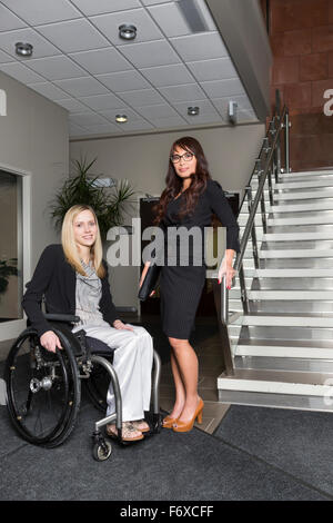 Ritratto di due attività professionali delle donne nella lobby di un ufficio, uno dei quali è un paraplegico in una sedia a rotelle; St. Albert, Alberta, Canada Foto Stock