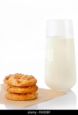 Pila di tre fatti in casa il burro di arachidi cookie sul foglio di carta forno e un bicchiere di latte, isolato su sfondo bianco Foto Stock