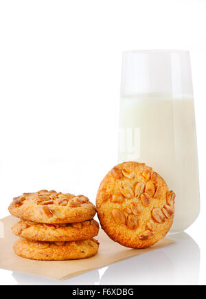 Pila di tre fatti in casa il burro di arachidi cookie sulla carta da forno, singolo cookie e il bicchiere di latte, isolato su sfondo bianco Foto Stock