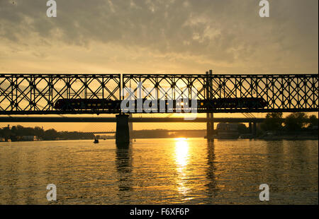 A Belgrado, in Serbia - treno attraversa il ponte sul fiume Sava al crepuscolo Foto Stock