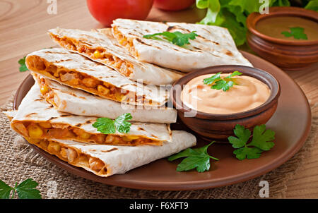 Mexican Quesadilla affettata con verdure e salse sul tavolo Foto Stock