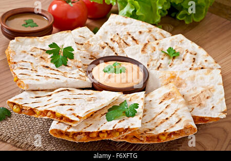 Mexican Quesadilla affettata con verdure e salse sul tavolo Foto Stock