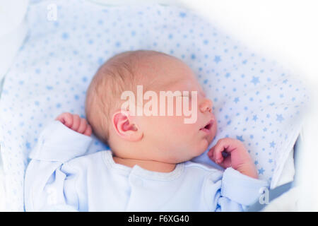 Neonato ragazzo nel letto. Il nuovo nato il bambino dorme sotto una maglia blu coperta. I bambini dormono. Biancheria da letto per bambini. Foto Stock