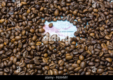 Mappa geografica della Papua Nuova Guinea coperto da uno sfondo di chicchi di caffè tostati. Questa nazione è uno dei principali produttori di un Foto Stock