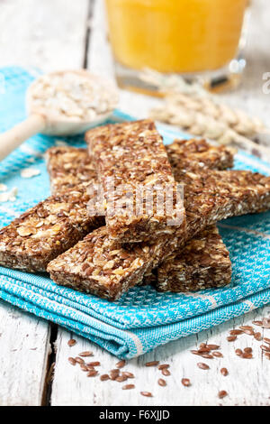 Barrette di cereali, fiocchi d'avena, semi di lino e il succo di arancia su uno sfondo di legno Foto Stock