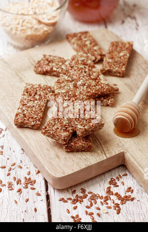 Barrette di cereali, fiocchi d'avena, semi di lino su uno sfondo di legno Foto Stock