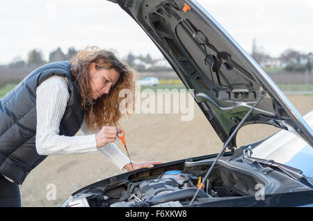 Donna 's auto si rompe e lei è un controllo del livello dell'olio Foto Stock