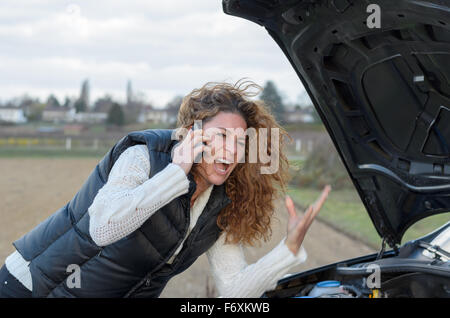 Donna 's auto si rompe e lei è chiamare i servizi di emergenza Foto Stock