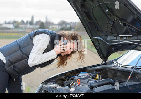 Donna 's auto si rompe e lei è chiamare i servizi di emergenza Foto Stock