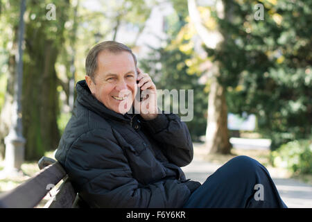 Uomo di mezza età utilizzando la nuova tecnologia il dispositivo in posizione di parcheggio Foto Stock