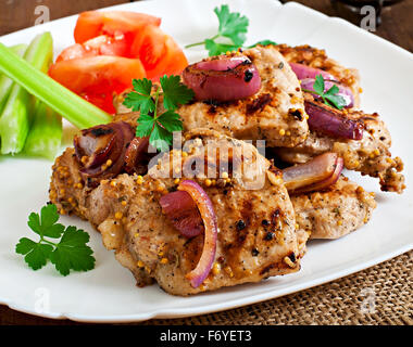 Fette di carne di maiale alla griglia con verdure su piastra bianca. Foto Stock